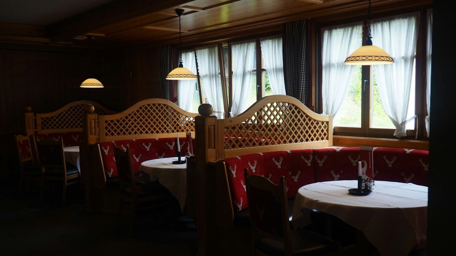 Stube mit Holzbänken und gedeckten Tischen