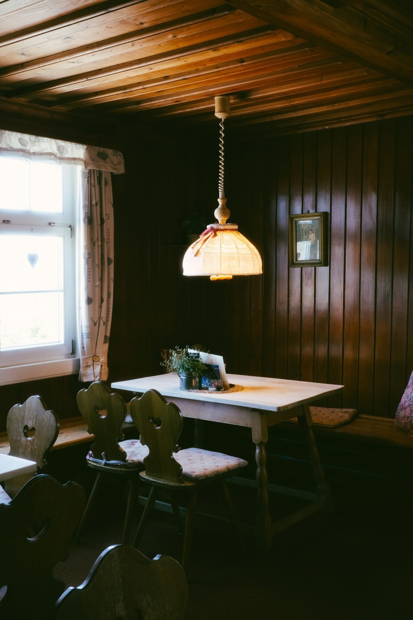 Holzvertäfelte Stube mit Tisch unter der Lampe
