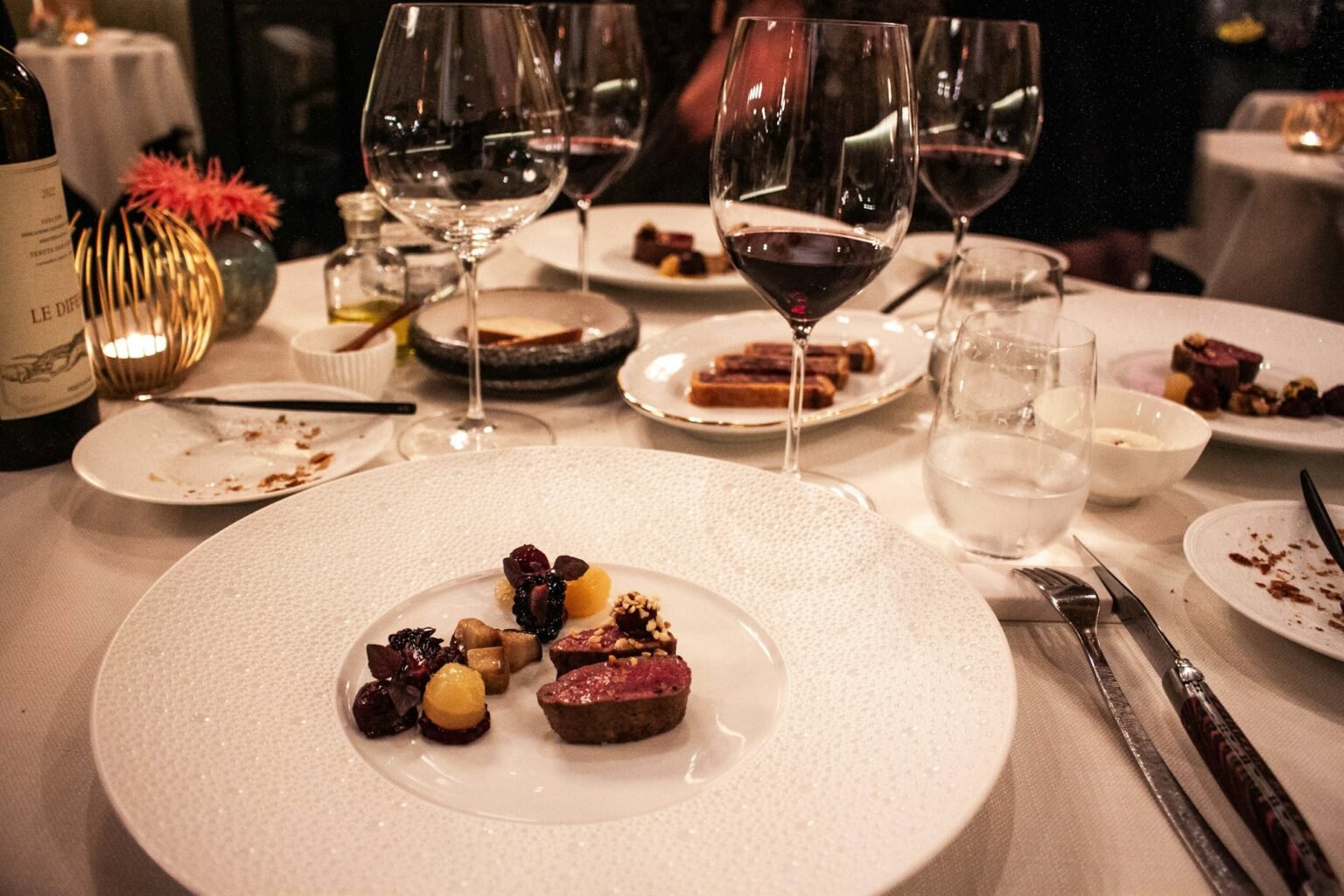 Gedeckter Tisch mit Rotwein und Hauptgang